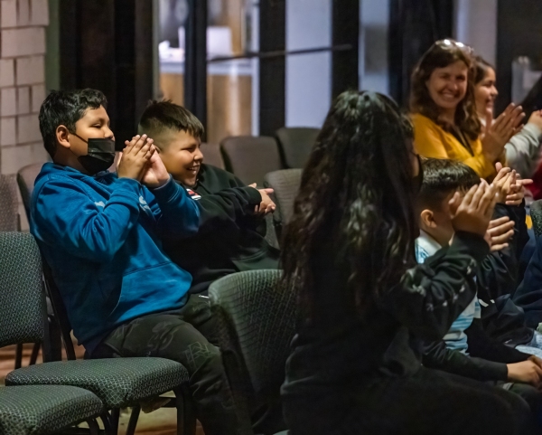 Young students seated in audience clapping at our Jazz for the Schools program. Students smile towards stage.