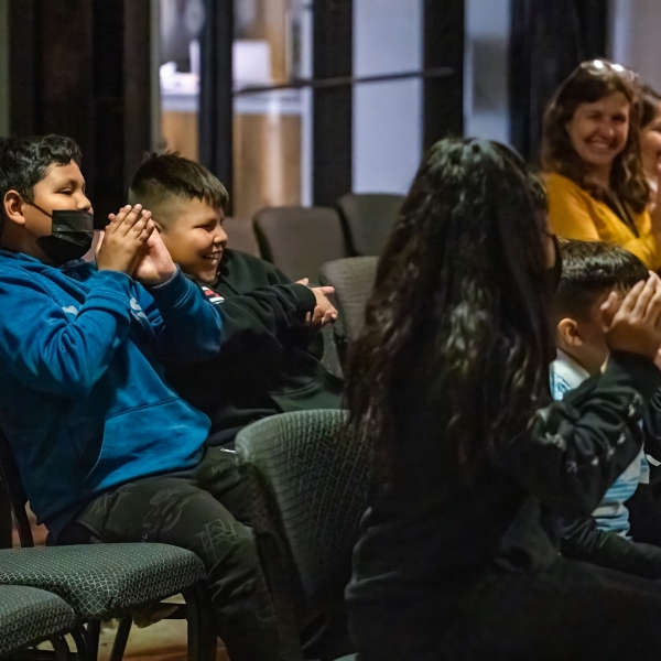 Young students seated in audience clapping at our Jazz for the Schools program. Students smile towards stage.