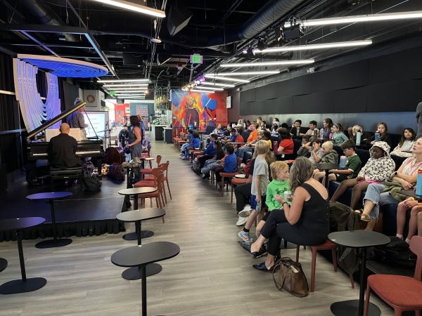 Students gather seated at Dazzle jazz club for Gift of Jazz's presentation for schools