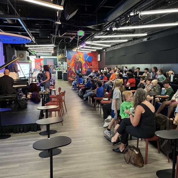 Students gather seated at Dazzle jazz club for Gift of Jazz's presentation for schools