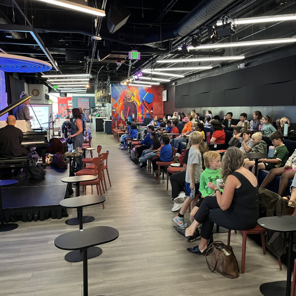 Students gather seated at Dazzle jazz club for Gift of Jazz's presentation for schools